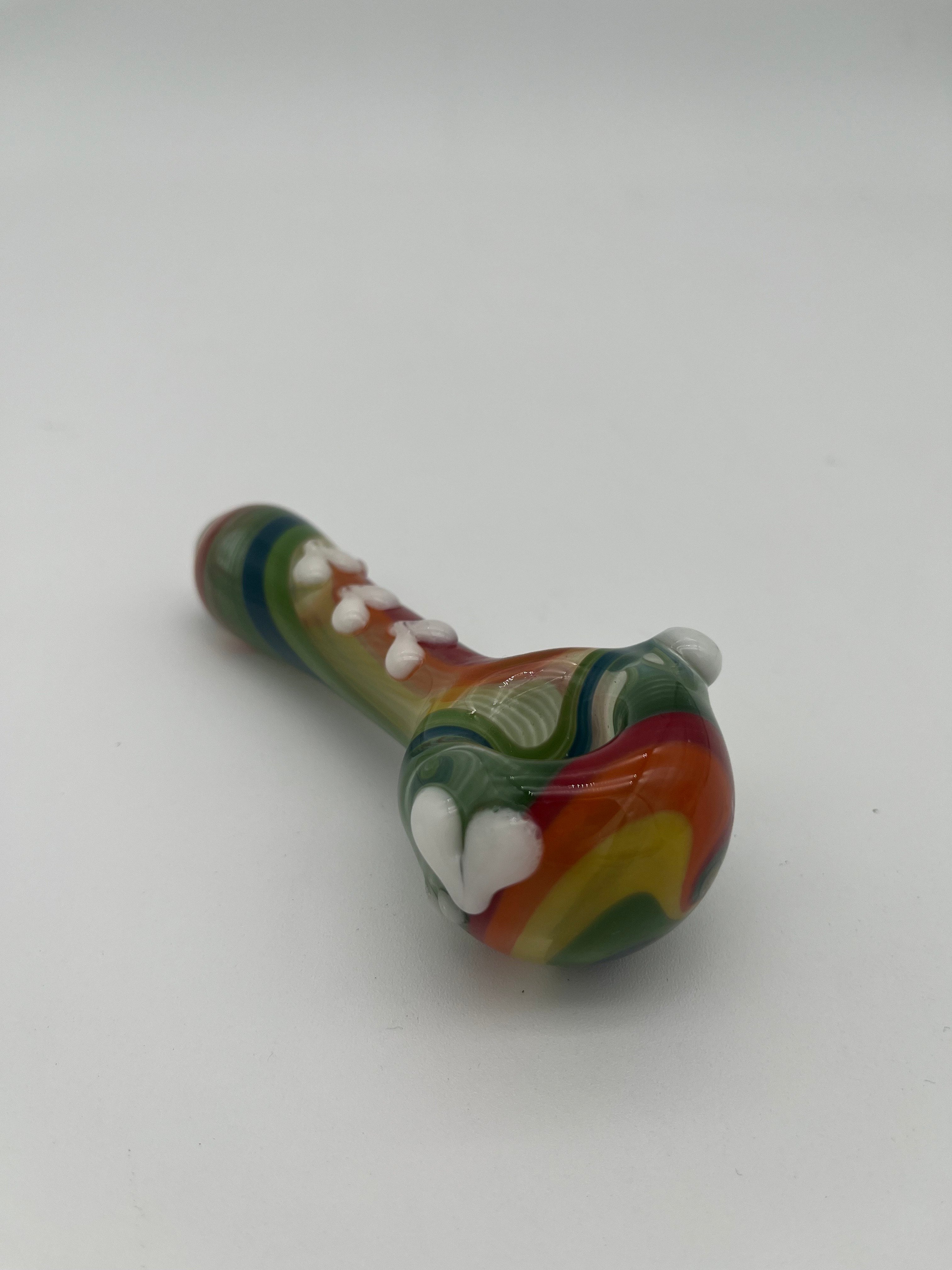 Rainbow glass pipe with white heart detailing on it displayed on a white background. Made by Kristi Conant.