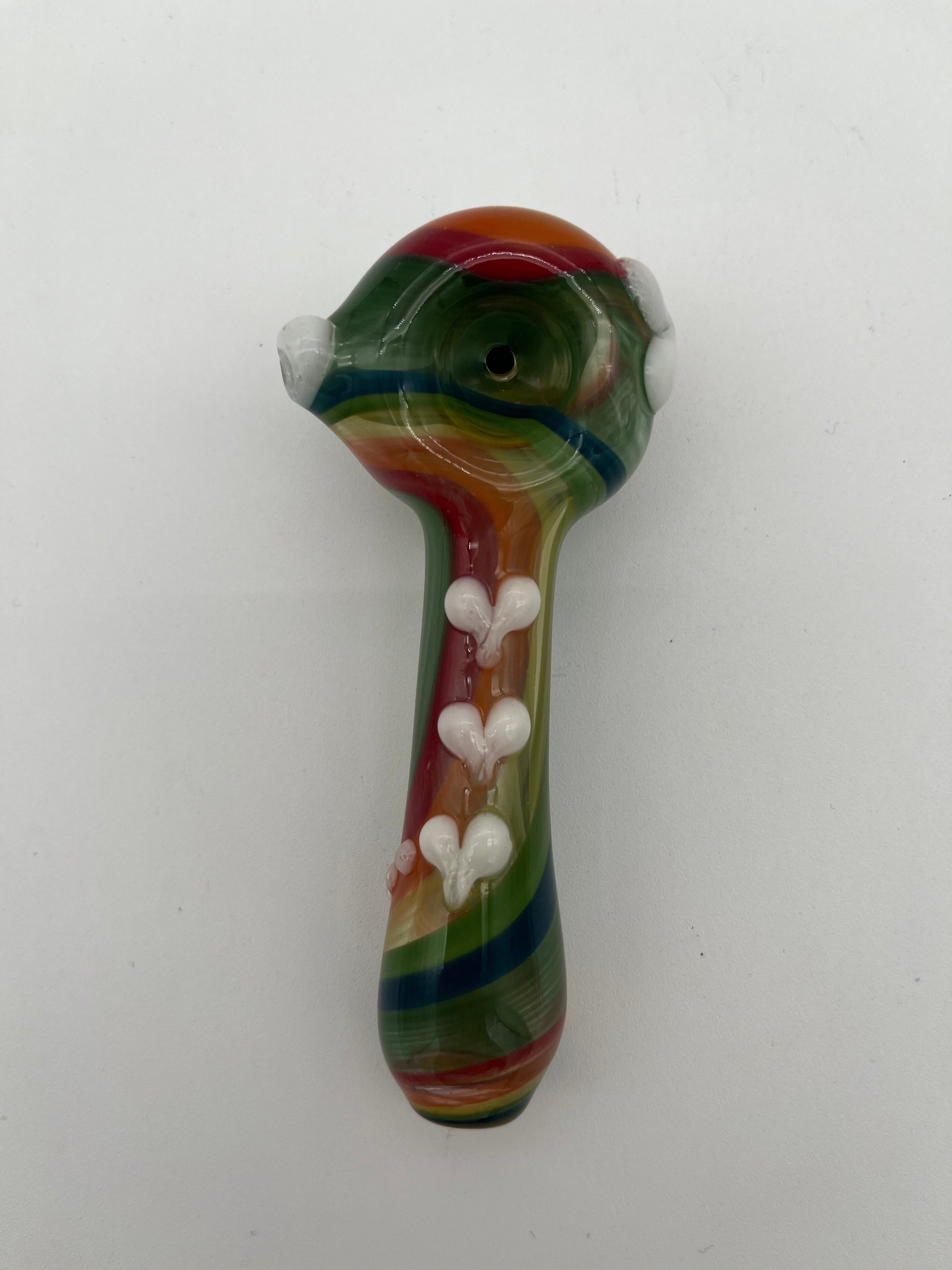 Rainbow glass pipe with white heart detailing on it displayed on a white background. Made by Kristi Conant.