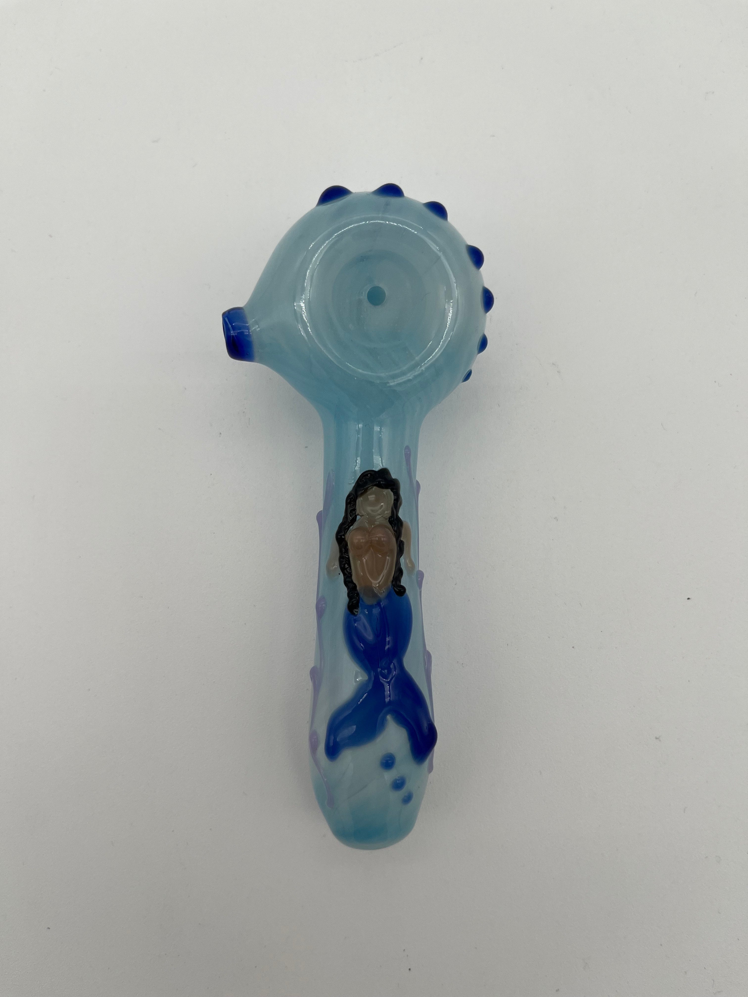 Light blue glass pipe with blue accents  and a mermaid on the top of it made by Kristi Conant on a white background