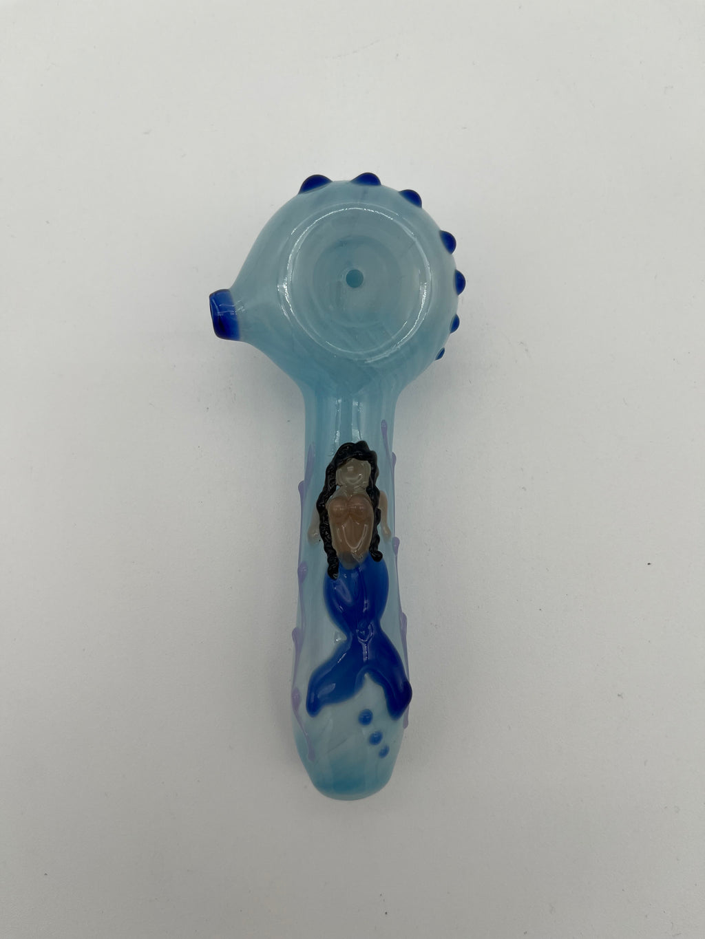 Light blue glass pipe with blue accents  and a mermaid on the top of it made by Kristi Conant on a white background