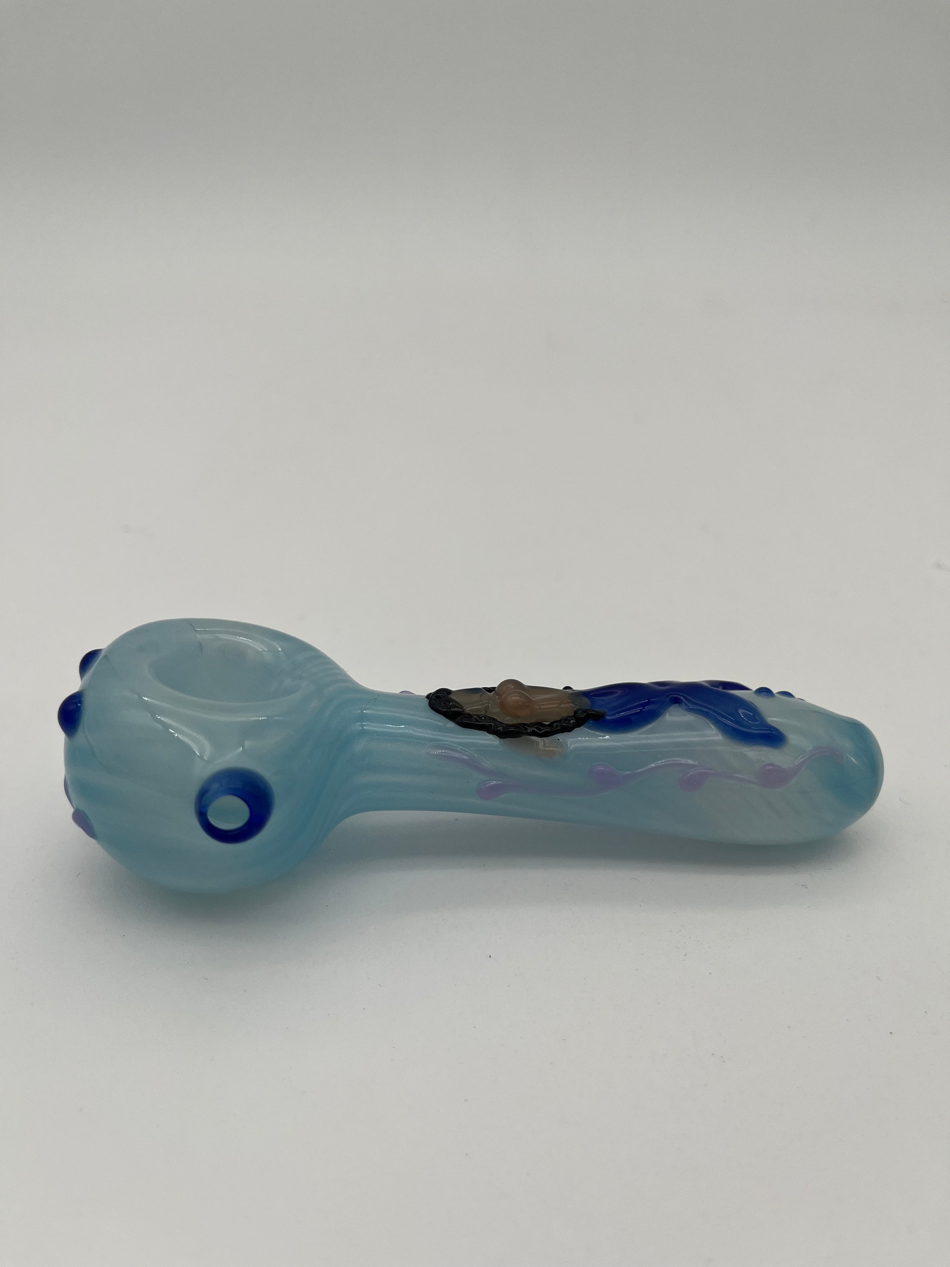 Light blue glass pipe with blue accents  and a mermaid on the top of it made by Kristi Conant on a white background