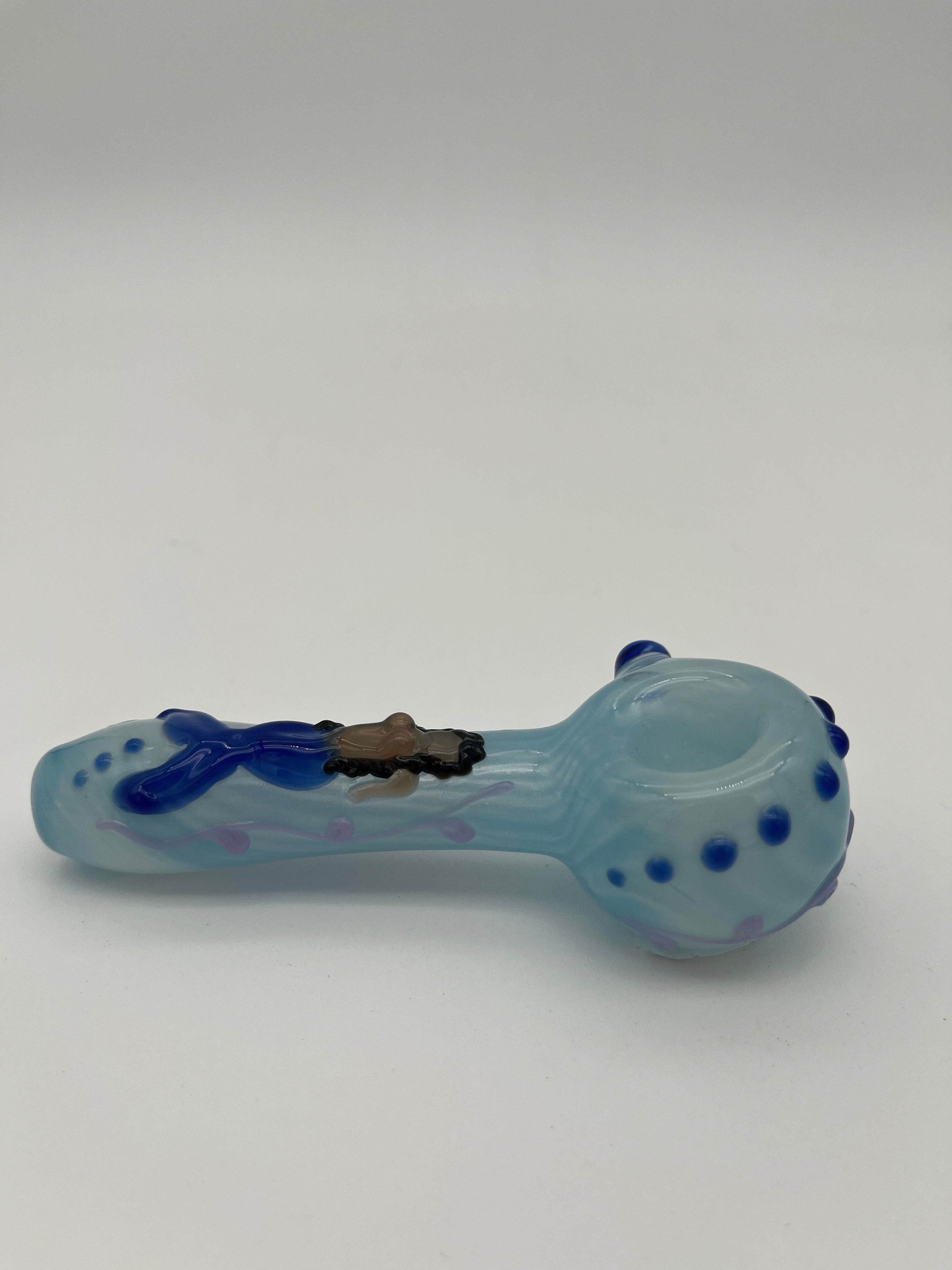 Light blue glass pipe with blue accents  and a mermaid on the top of it made by Kristi Conant on a white background