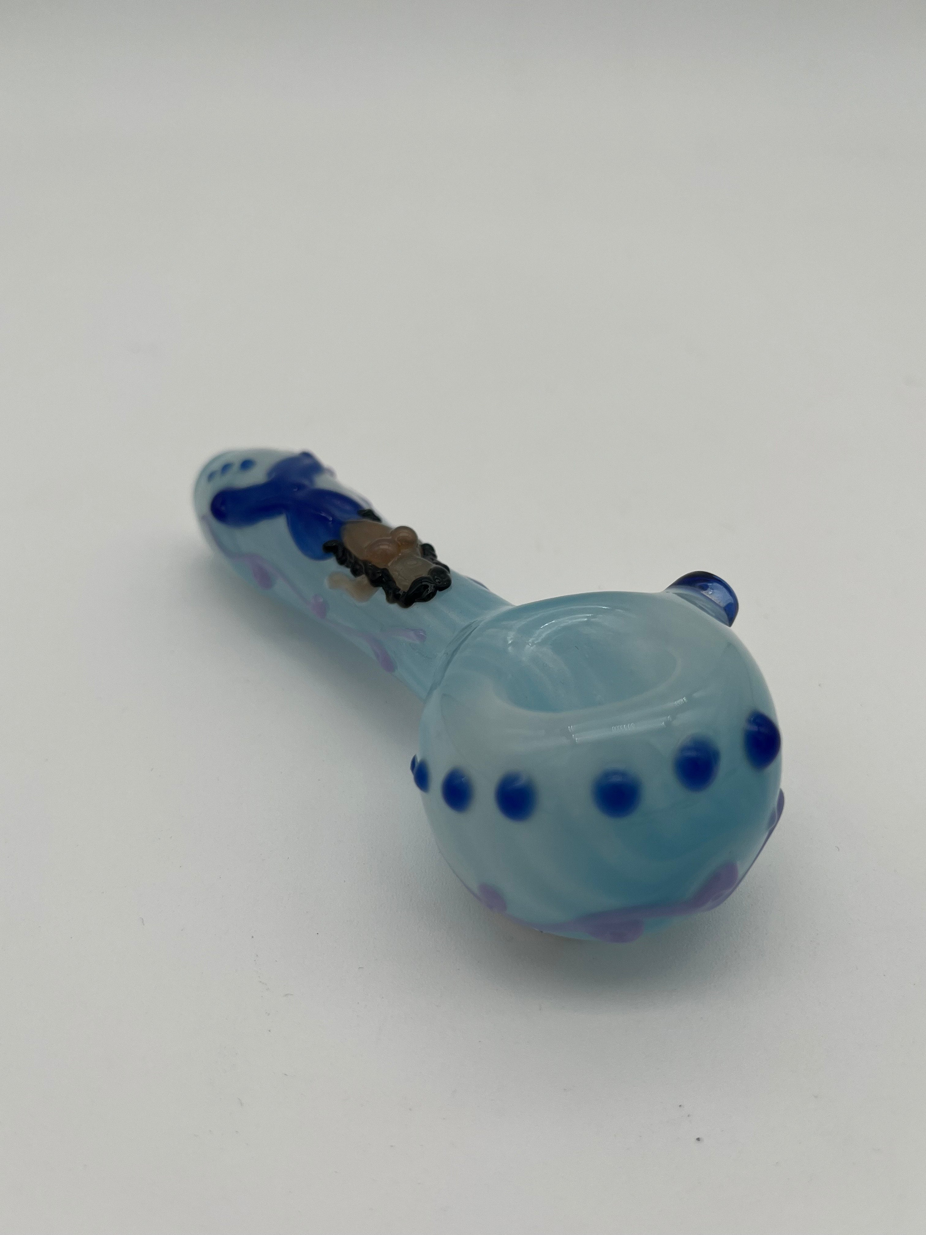 Light blue glass pipe with blue accents  and a mermaid on the top of it made by Kristi Conant on a white background