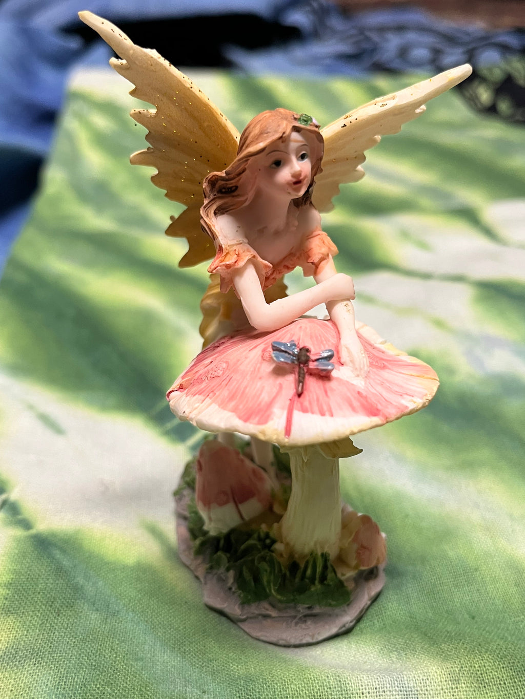 Fairy figurine with pink parasol on a green leaf background