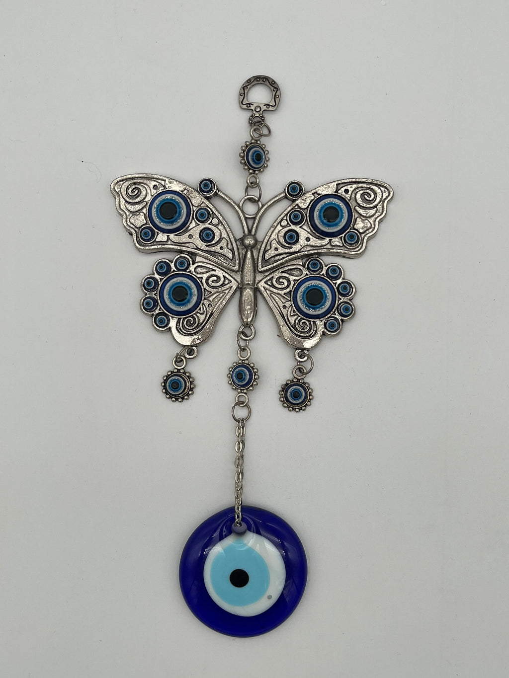 Butterfly-shaped pendant with blue evil eye design on a white background